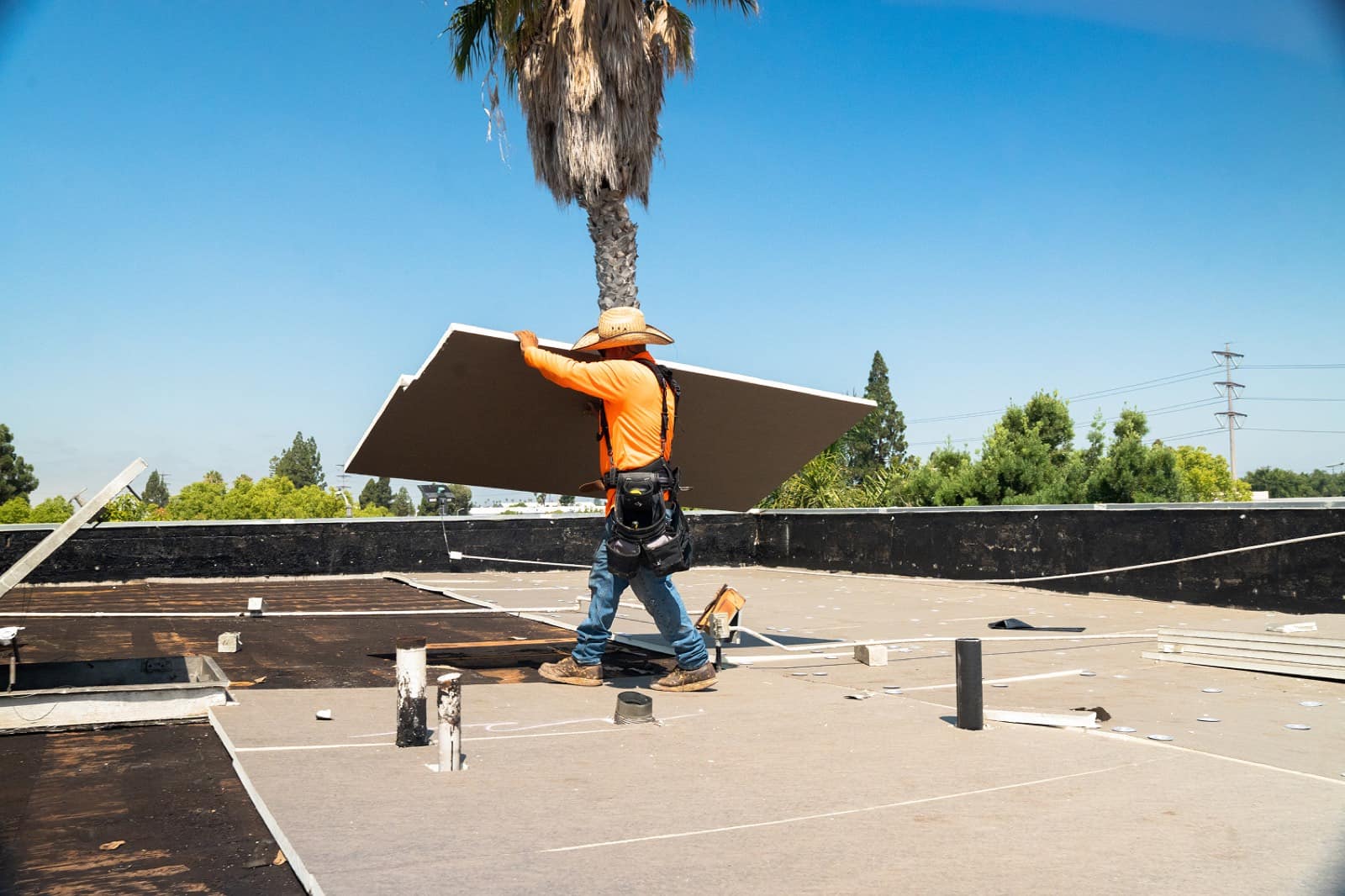 SoCal Roofers crew member installing roof insulation board on a Southern California commercial roof